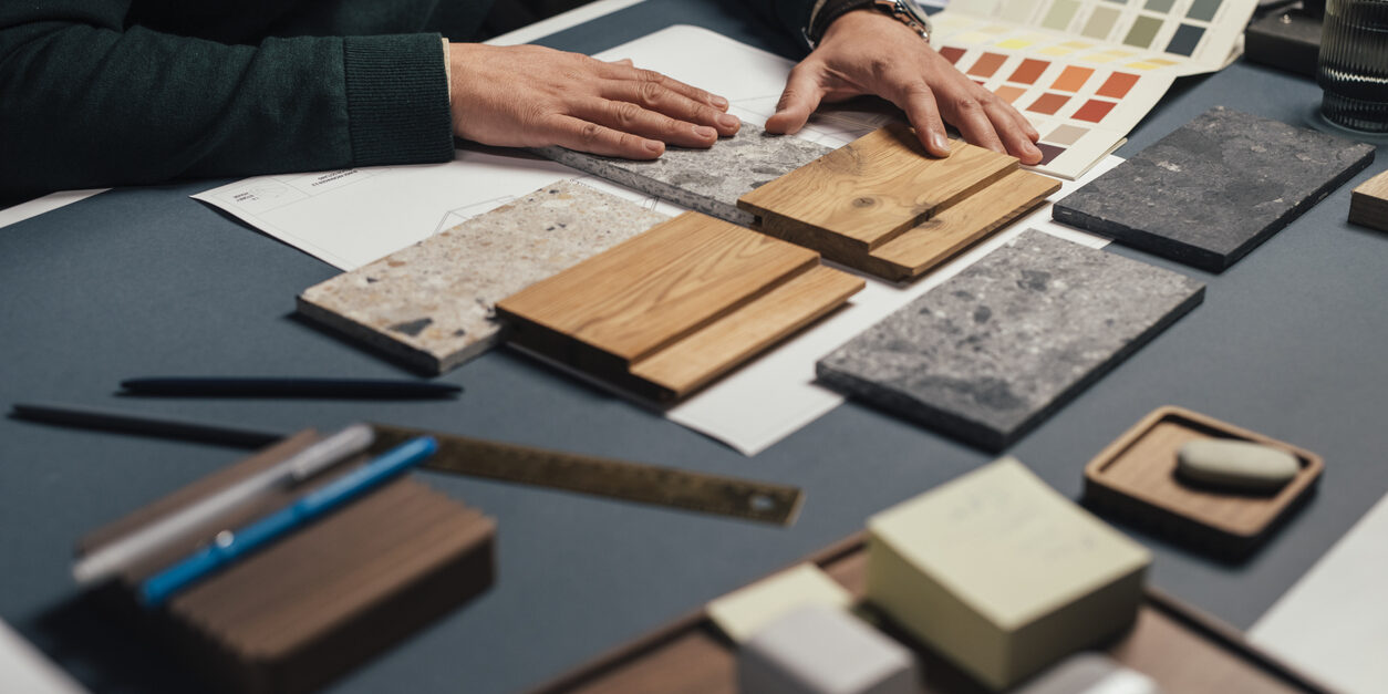 Hands of an Anonymous Male Interior Designer Comparing Samples of Different Materials in his Office